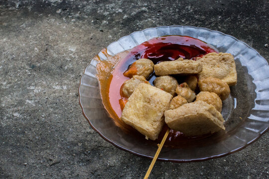 Portrait of Indonesian somay and street meatballs placed on a cement floor, capturing authentic local street food atmosphere and texture.
