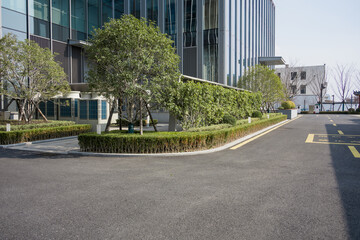 Obraz premium Modern office building with landscaped green belt and asphalt pavement in front