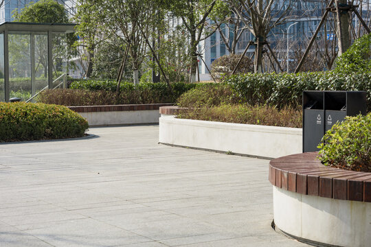 Urban park plaza with paved walkways, greenery, and modern seating facilities