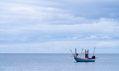 Sea water beach with small fishing boat floating on under blue sky cloudy.Horizon summer seascape with copy space for taxt sale,promotion presentation,peaceful ocean, tranquil travel nature background