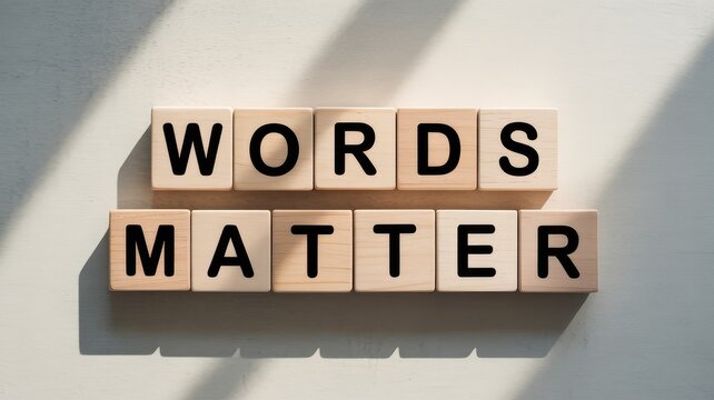 Wooden letter tiles spelling Words Matter on a light surface with strong natural sunlight casting shadows highlighting the message