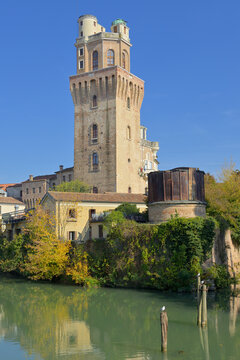 Specola Astronomical Observatory tower standing by Bacchiglione river in Padua. Medieval tower of the Specola Astronomical Observatory reflecting on the tranquil river water.
