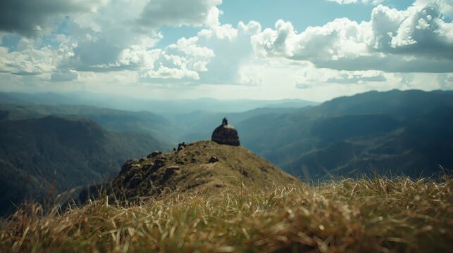 Person on hilltop overlooking mountain range under cloudy sky