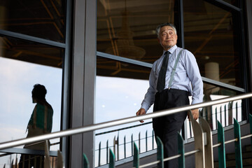 Senior businessman descends stairs in a modern office