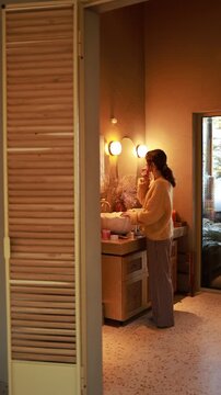 Slow living video of a woman performing morning face care routine in a luxurious bathroom. Warm light, calm movements, minimalist design and serene self care atmosphere in a modern home