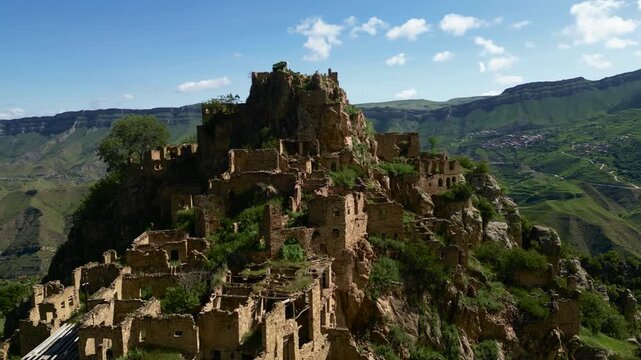 Drone aerial view of the abandoned mountain village of Gamsutl in Dagestan at sunrise with soft golden morning light and dramatic scenery.