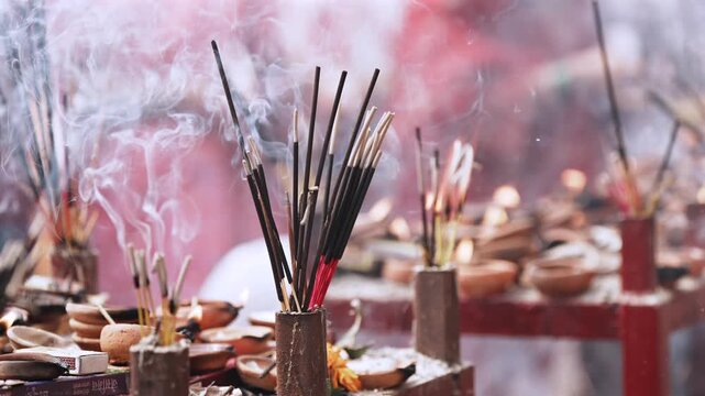 Smoke rises from burning incense sticks during a religious ritual, adding to localised air pollution and creating a hazy atmosphere