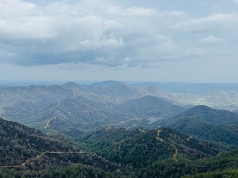 Scenic viewpoint Pefkos tis Louvarous in Cyprus, overlooking lush pine forests, rolling hills, and distant mountain ridges under clear Mediterranean sky