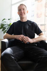 Fototapeta premium Young man smiling sitting inside a modern office