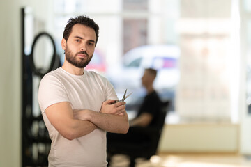 Barbershop owner with scissors portrait in hair salon