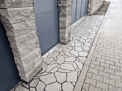 concrete composite paving unique imitation of stacked natural stone, driveway to family house and courtyard. chipped stone with pronounced joint, perforated sheet metal gates made of gray sheet metal