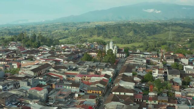 drone flying at the door to the city filandia exposing the outside of the city to the main plaza incluiding the main church in the plaza in quindio colombia in a sunny day