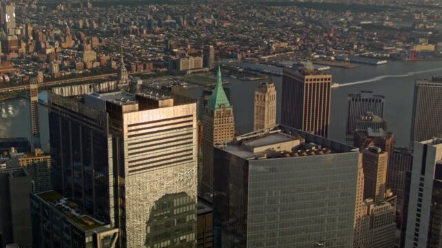 High view of Wall Street and neighboring buildings in New York City as a boat moves along the East River and the Brooklyn skyline fills the background - handheld camera