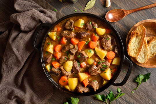 Beef stew with potato, carrot, onion, herbs in cast iron pan