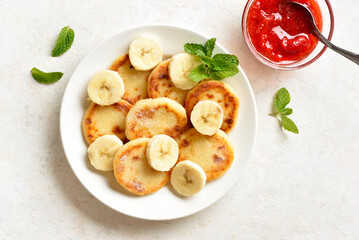 Delicious curd cheese pancakes with banana slices served with strawberry sauce