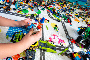Fototapeta premium Child Playing With Lego Bricks Building Rocketship On Colorful Play Mat