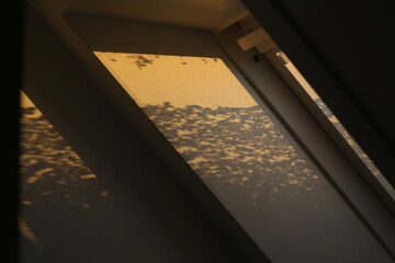 snow on the dormer window with the sun shining on it and shadows on the wall from it