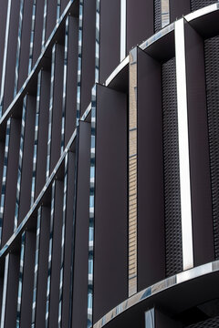 Urban architecture detail of dark modern building facade with office lines and abstract pattern suggesting late day corporate background