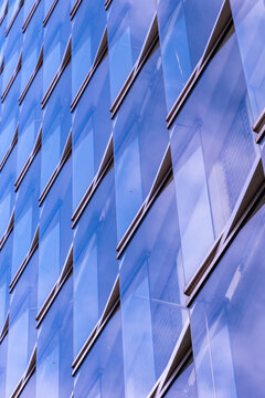 Modern office building with blue glass facade and reflections creating abstract pattern over architecture detail for clean design background