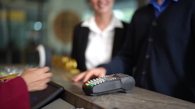 Close up of hand processing credit card payment on hotel front desk terminal during business trip check in. Corporate travel, secure transaction and professional hospitality service concept.