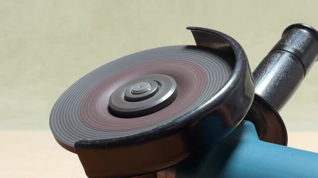 The electric grinder is switched off, causing the spinning disc to lose momentum. As the rotation slows, the sharp metallic scream descends into a low, rhythmic whirring sound.