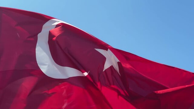 The Turkish flag flutters in the wind, the flag against a blue sky. High quality 4k footage