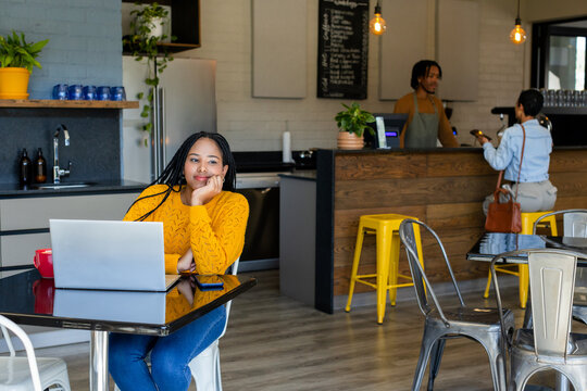 Female typing on laptop at coffee shop table with red mug smartphone, copy space