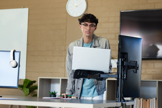 Man standing behind lectern adjusting laptop on mount at modern office workspace