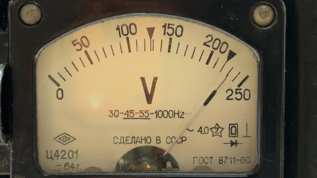 An old Soviet voltmeter displays a live reading on its aged yellow dial. As the electrical current flows through the internal coils. This process results in a deep, low-frequency humming sound.
