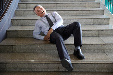 Senior man falling down the stairs, in pain and distress. He is wearing formal attire, and is on a set of stairs