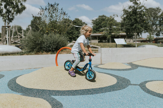 Happy girl riding scooter on a playground