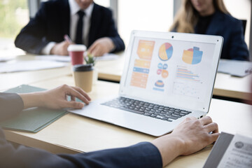 Fototapeta premium People colleague meeting with laptop showing colorful charts and graphs in modern office while business professionals discuss data and strategy over coffee and documents
