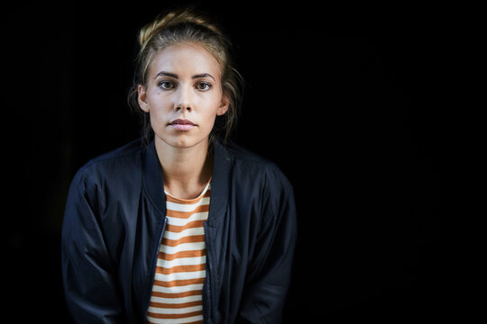 Portrait of a young woman in front of a black background