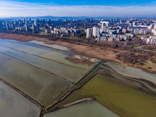 View of city skyline with salt flats in the foreground during daylight, showing the blend of urban environment and natural landscape