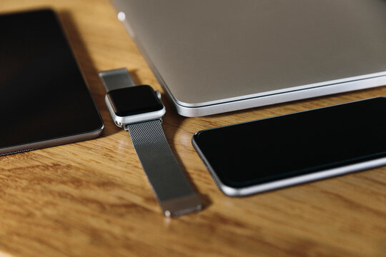 Tablet, smartwatch, smartphone, and laptop on wood