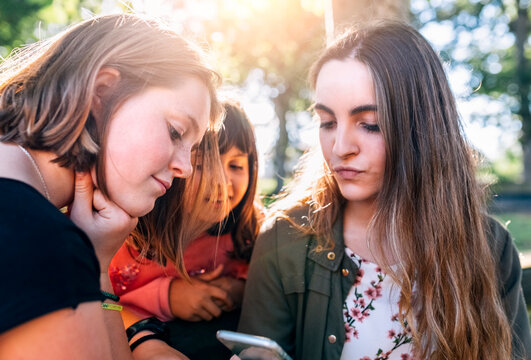 Three girls using smartphone outdoors