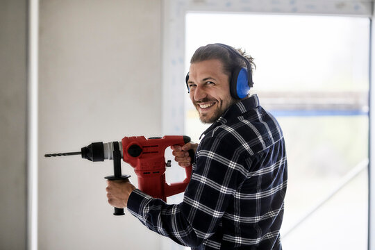 Portrait of smiling worker using electric drill on a construction site