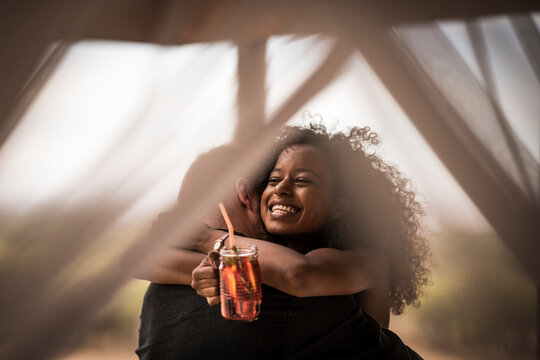 Happy woman holding fresh ice tea drink hugging man