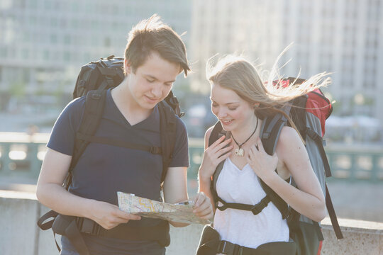 Germany, Berlin, Young couple traveling Berlin with backpacks, looking at map