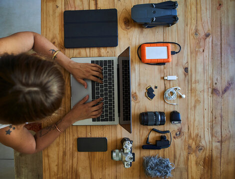 Person sitting at table with photografic equipment, using laptop, overhead view