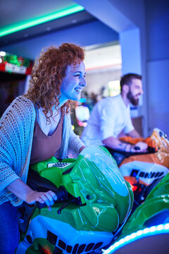 Woman playing and having fun with a driving simulator in an amusement arcade
