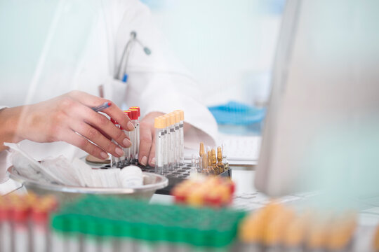 Close-up of lab technician with test tubes and rack in laboratory