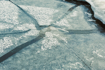 Cracked ice reflects light in a frozen lake during winter showing patterns and textures on the surface