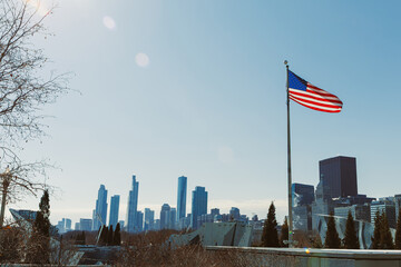 City skyline with American flag flying on a clear day in the background of tall buildings and open sky