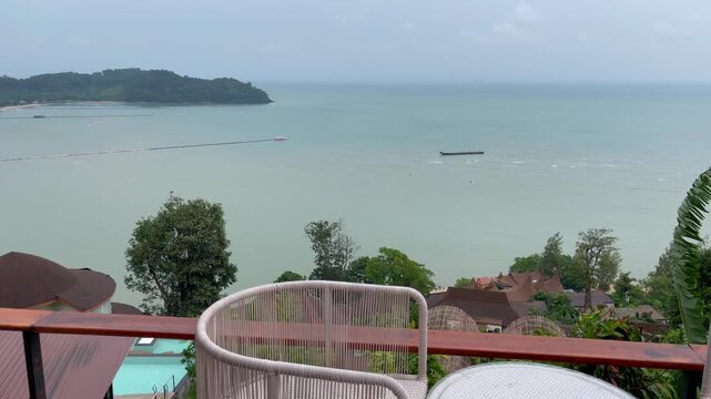 Scenic daytime view from a luxury resort restaurant terrace overlooking the calm sea, tropical coastline, and distant islands in Cape Panwa, Phuket, Thailand