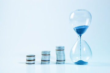 Time is money concept. Hourglass and coins on white background.