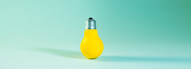 Yellow light bulb on a blue background. Minimalism concept.