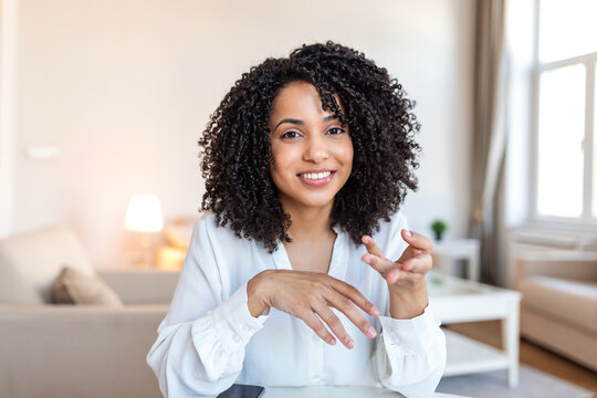 Video call conversation. Online meeting discussion, People with digital communication concept. Friendly diverse woman sitting at desk, gesturing with hands while talking toward the laptop webcam.