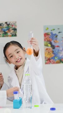 Young Asian Girl in Lab Coat Demonstrating Bernoulli's Principle Experiment