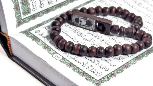 Quran and Prayer Beads: An open Quran lies peacefully, its intricate pages adorned with script, alongside a string of prayer beads, each bead reflecting a devotion.